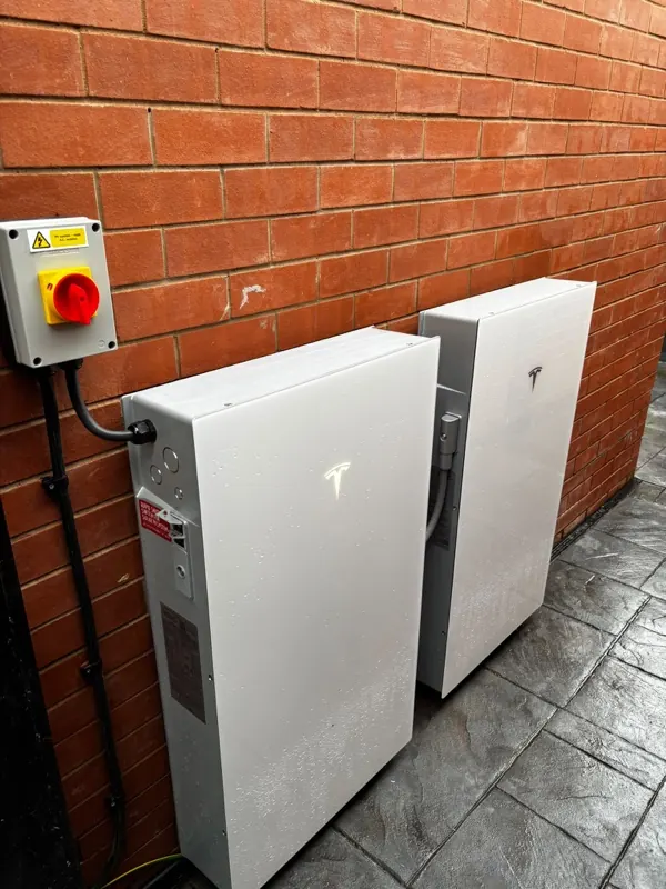 Two Tesla Powerwall batteries mounted next to each other on brick