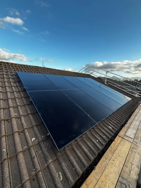 Black solar panels on a tiled roof against a clear sky